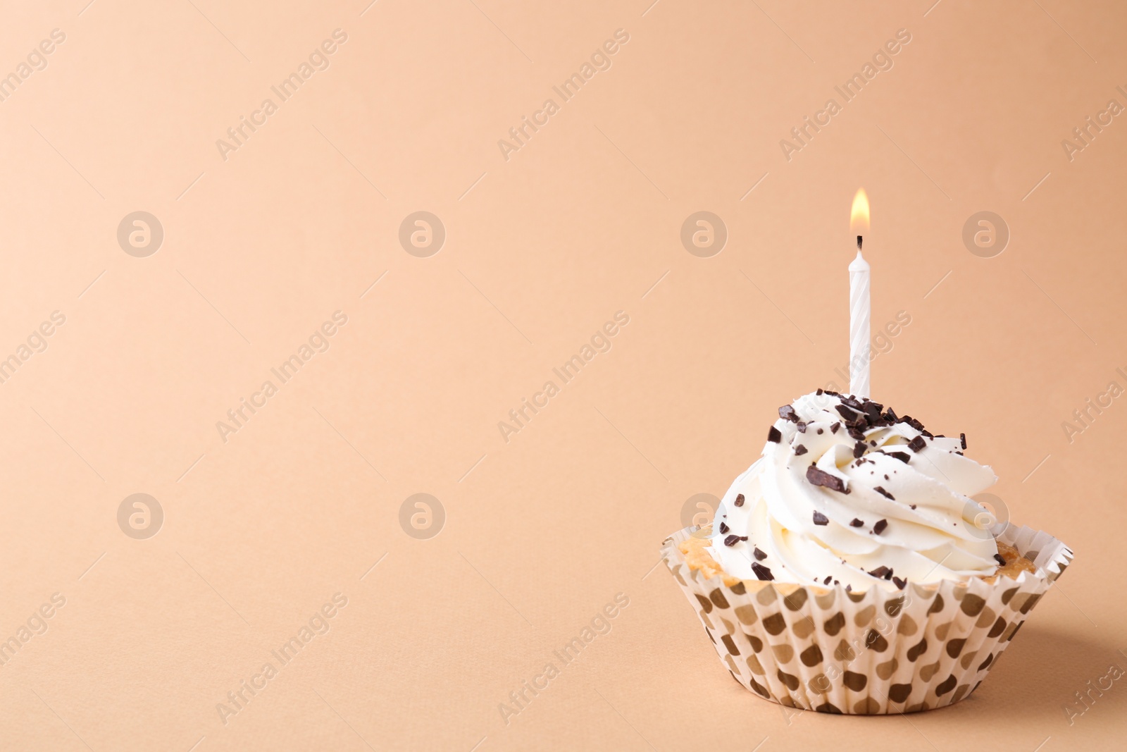 Photo of Delicious birthday cupcake with candle on beige background. Space for text