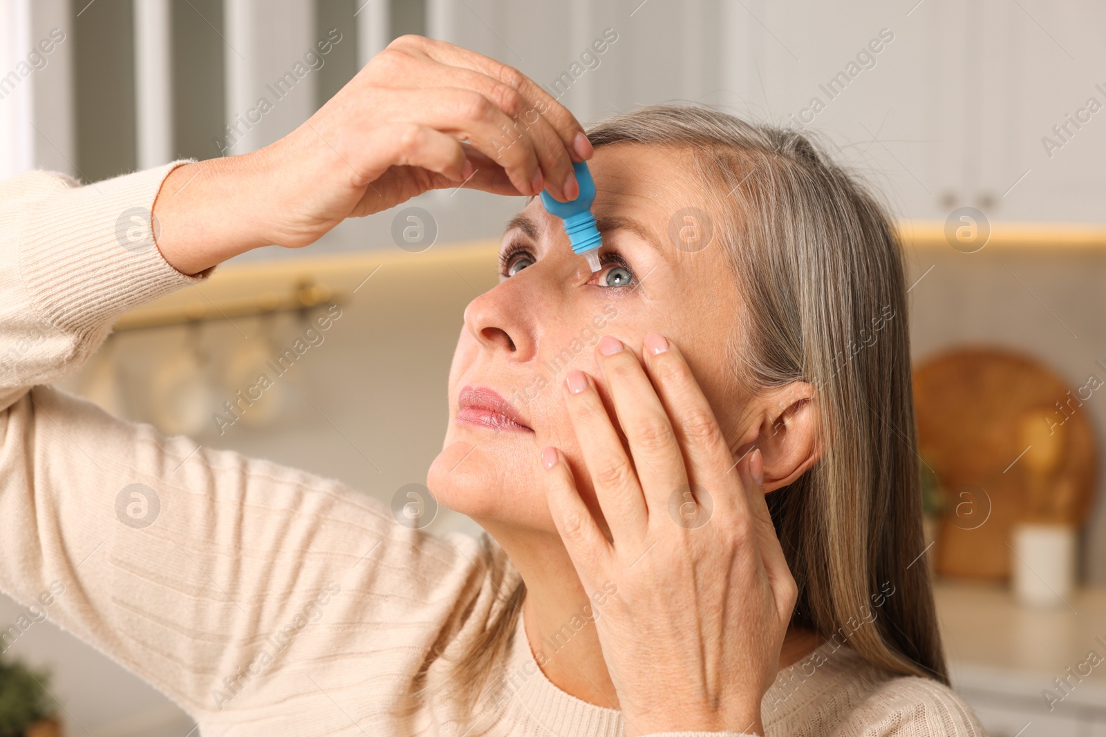 Photo of Woman applying medical eye drops at home