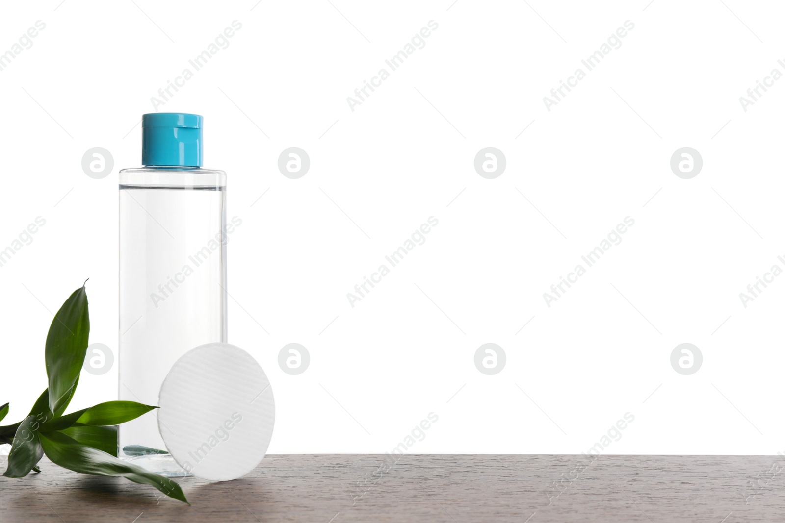 Photo of Micellar water in bottle and cotton pads on wooden table against white background. Space for text