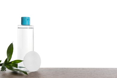 Photo of Micellar water in bottle and cotton pads on wooden table against white background. Space for text