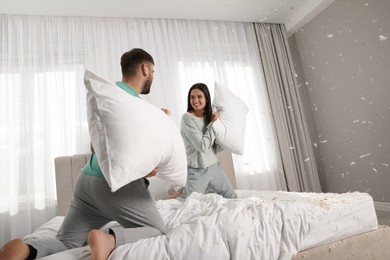 Photo of Happy young couple having fun pillow fight in bedroom