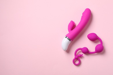 Photo of Anal balls and vibrator on pink background, flat lay with space for text. Sex toys