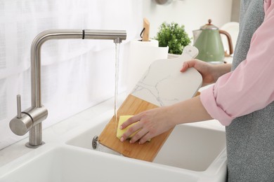 Photo of Woman washing cutting board at sink in kitchen, closeup