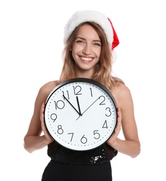 Happy young woman in Santa hat holding clock on white background. Christmas celebration