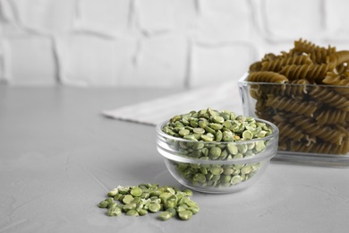 Photo of Dry green peas and pasta on light grey table. Space for text