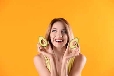 Portrait of young beautiful woman with ripe delicious avocado on color background