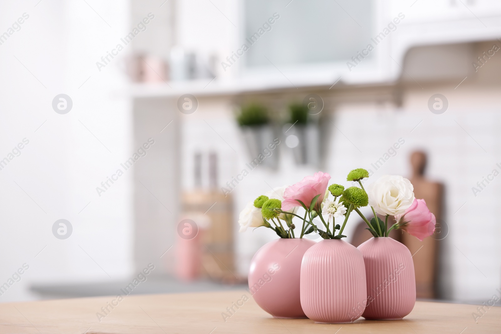 Photo of Vases with beautiful flowers on table in kitchen interior. Space for text