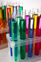 Photo of Many test tubes with colorful liquids on grey background, closeup