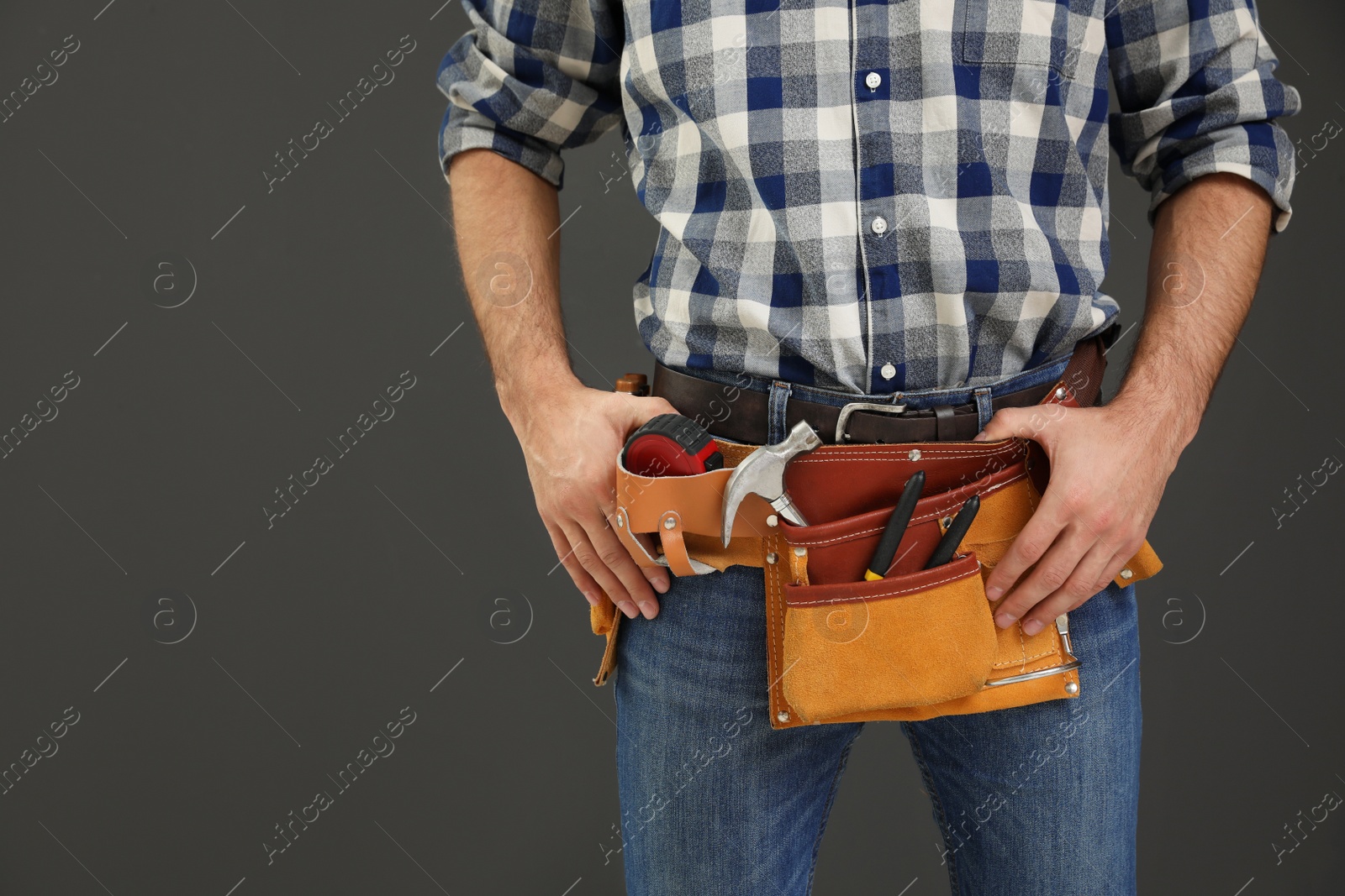 Photo of Carpenter with tool belt on dark background, closeup