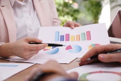 Photo of Business people working with charts and graphs at table in office, closeup. Investment analysis