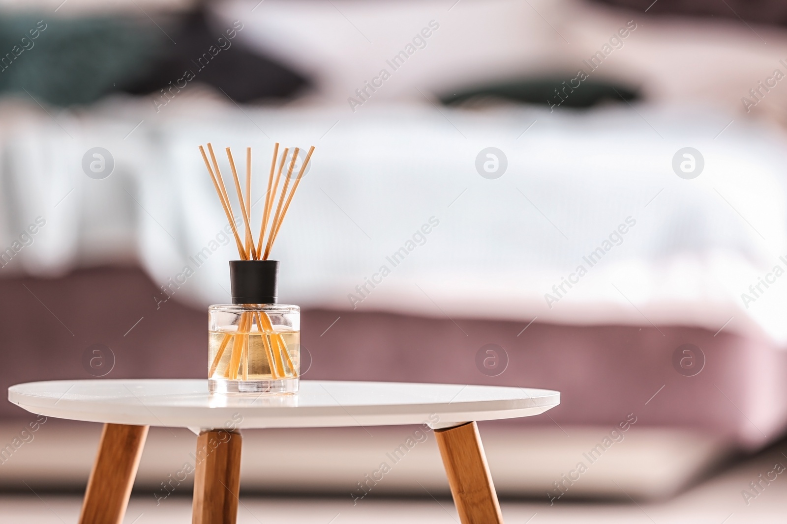 Photo of Aromatic reed air freshener on table against blurred background