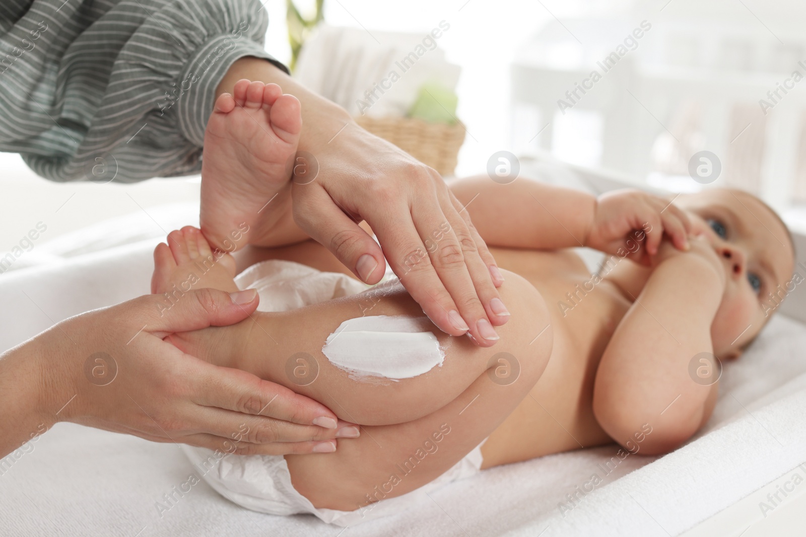 Photo of Mother applying body cream on her little baby at home, closeup