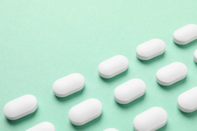 Many white pills on green background, space for text