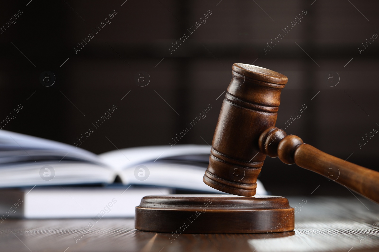 Photo of Wooden gavel and books on table against blurred background, closeup. Space for text
