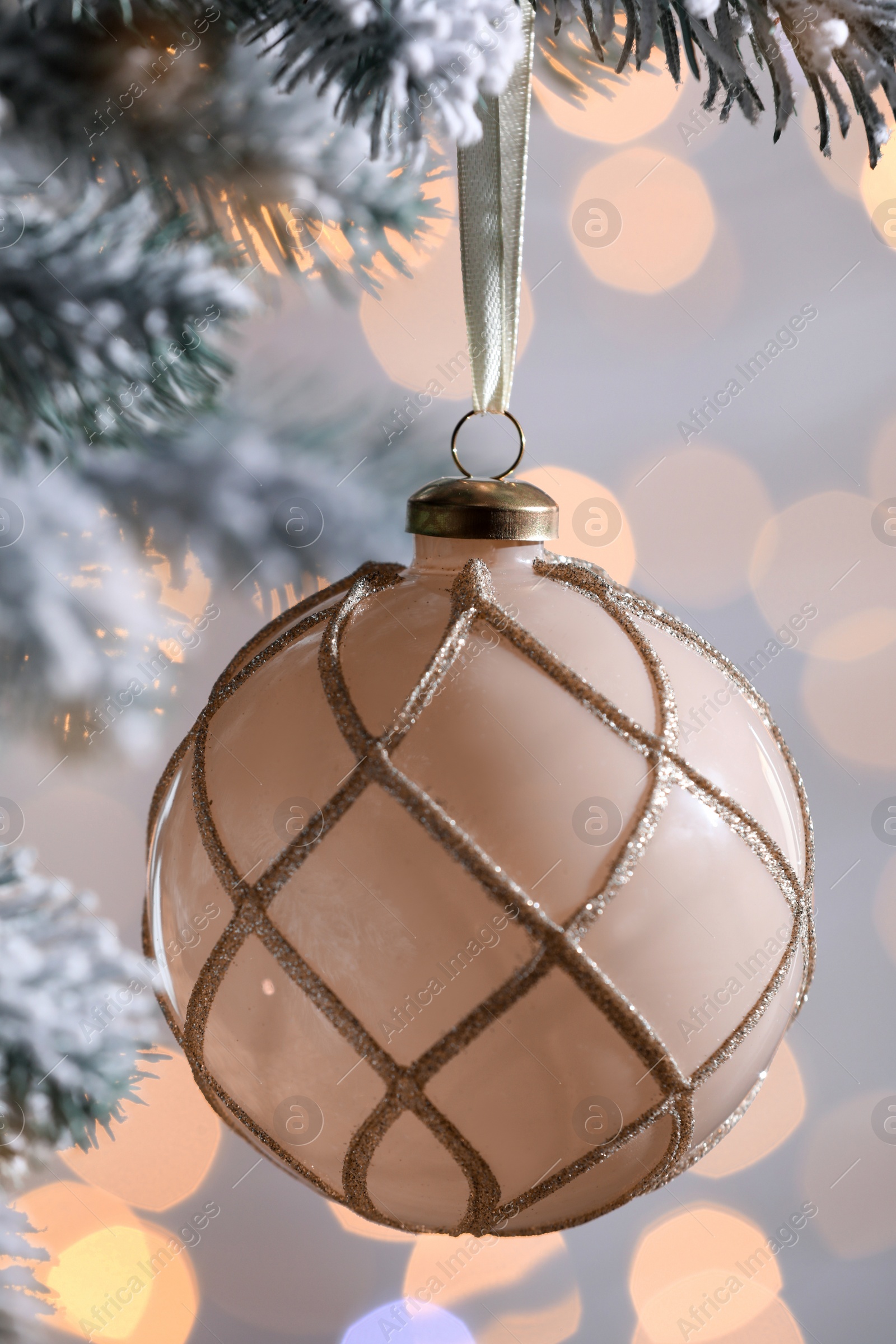 Photo of Christmas tree decorated with holiday ball against blurred lights, closeup