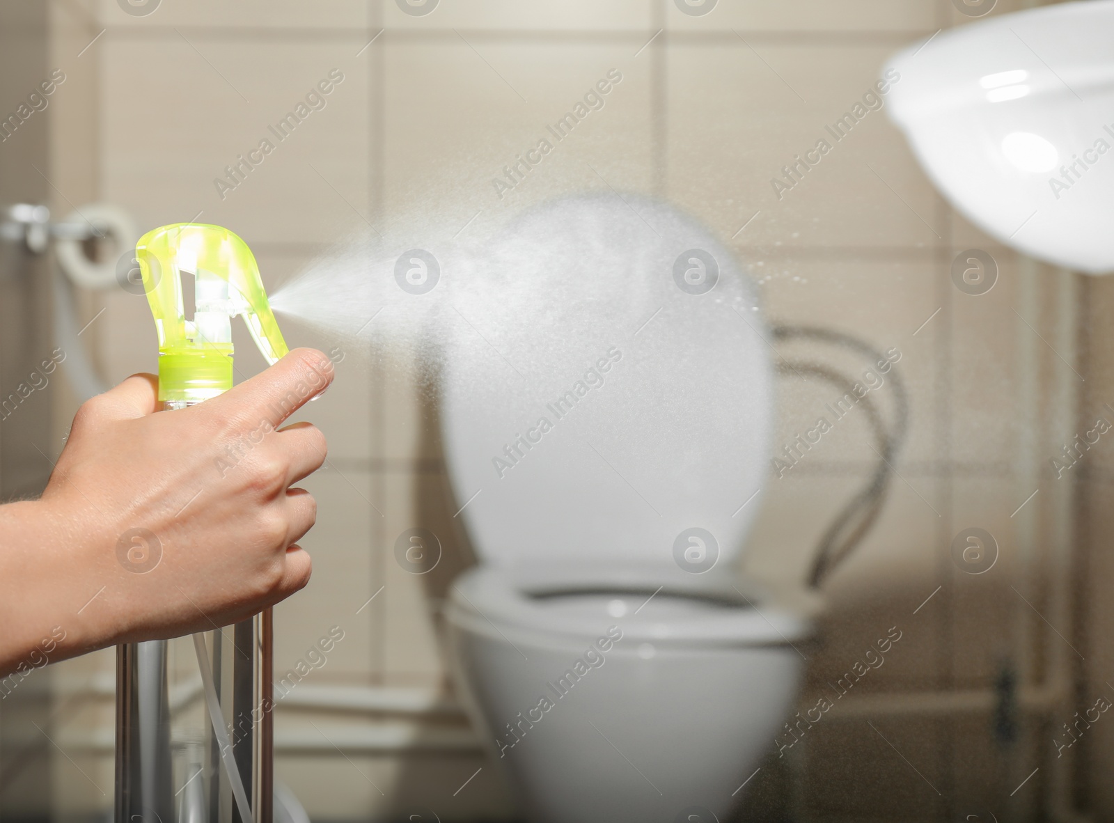 Photo of Woman spraying air freshener in bathroom