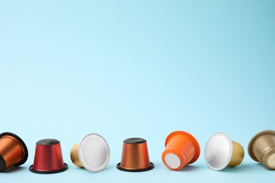 Photo of Many coffee capsules on light blue background, space for text