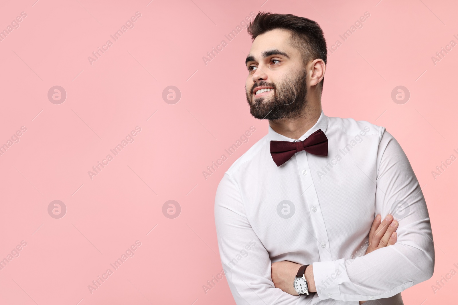 Photo of Portrait of smiling man in shirt and bow tie on pink background. Space for text