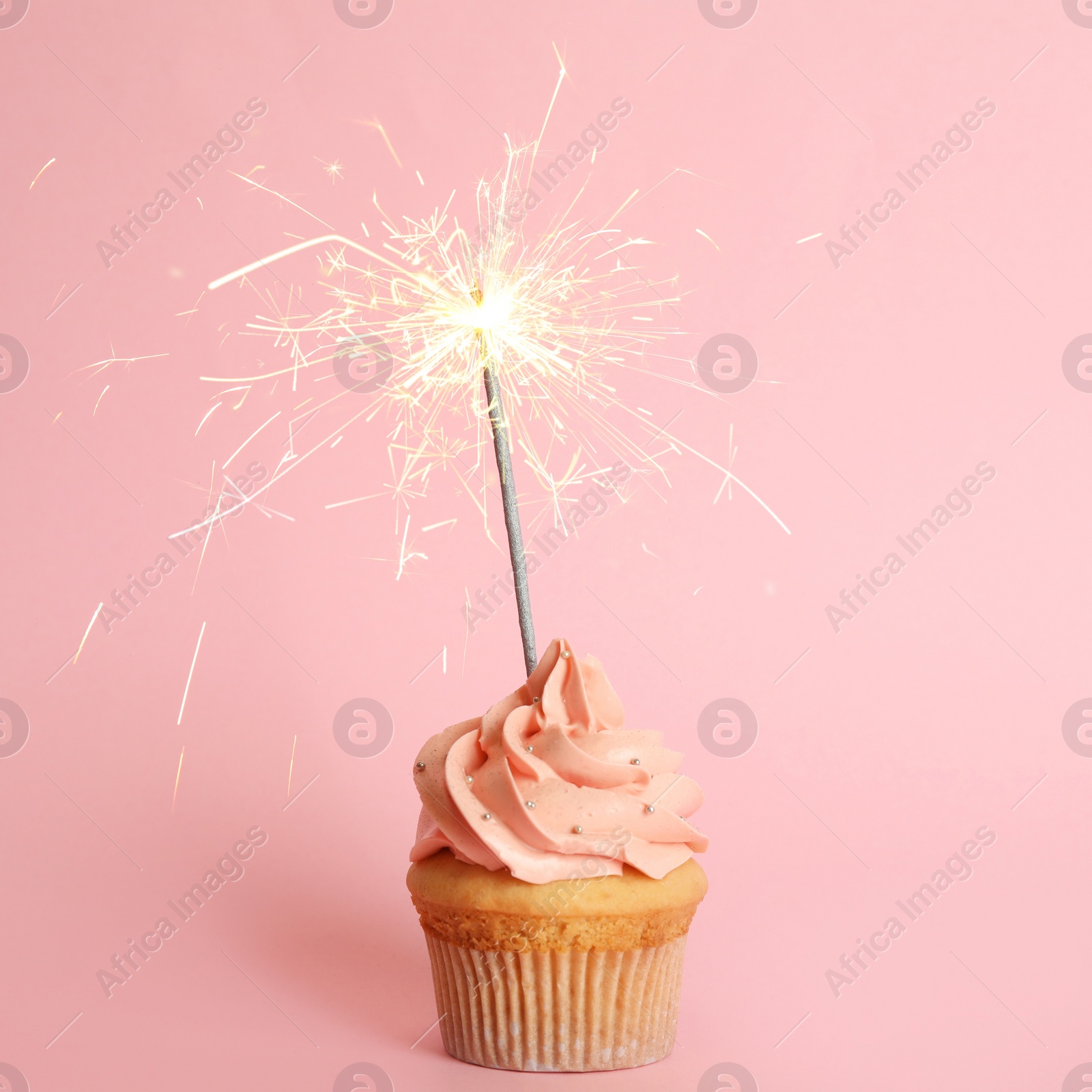 Image of Birthday cupcake with sparkler on pink background