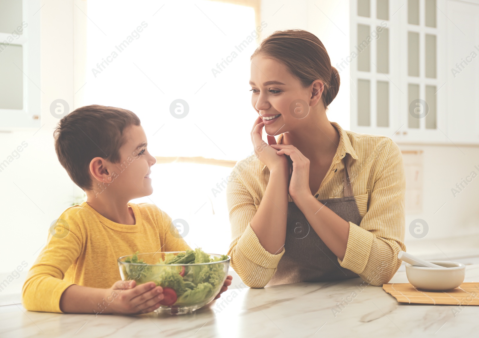 Photo of Mother and son cooking salad together in kitchen