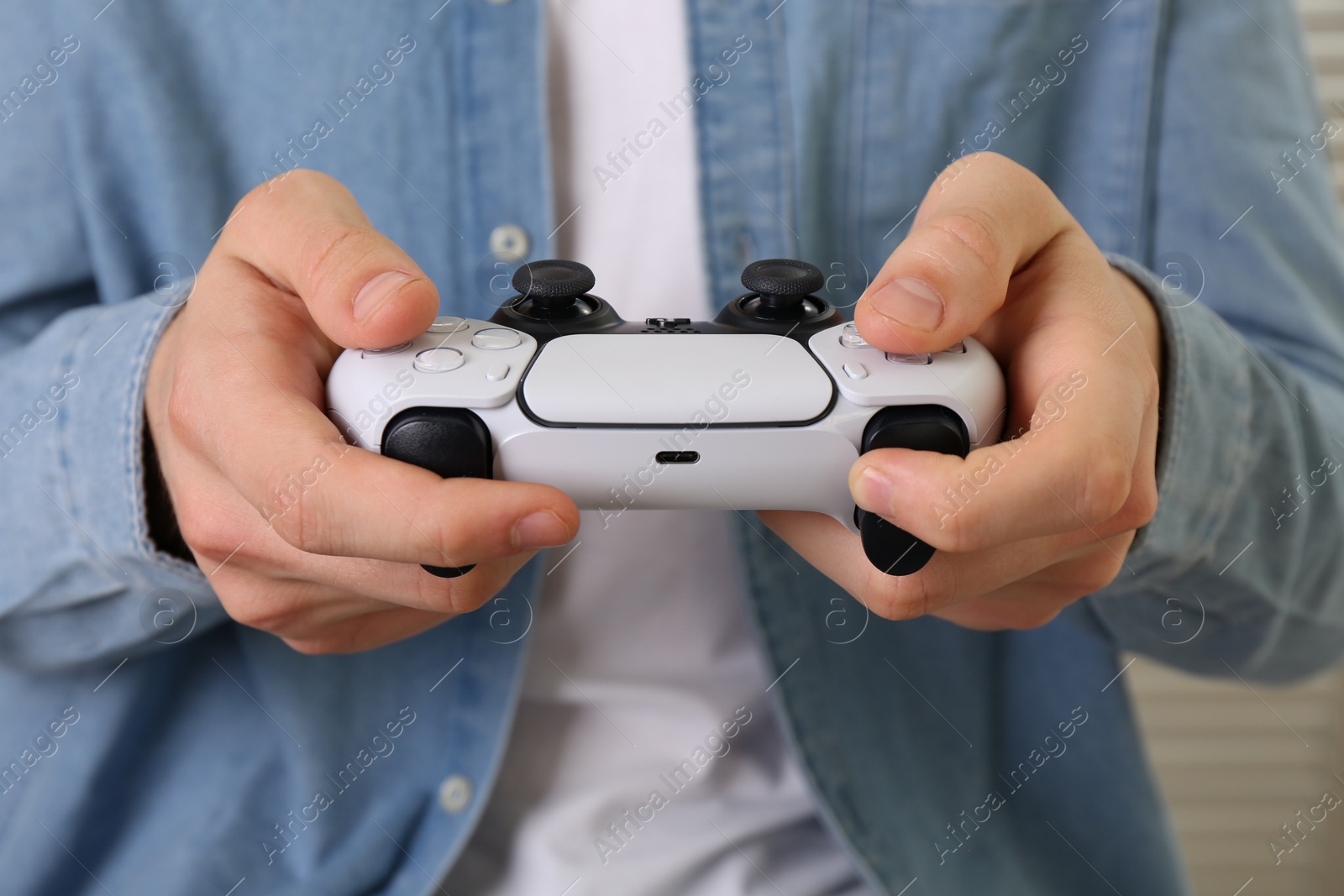 Photo of Man using wireless game controller indoors, closeup