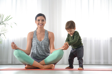 Photo of Young woman meditating with her son at home