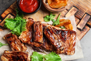Delicious grilled ribs and garnish on table, closeup