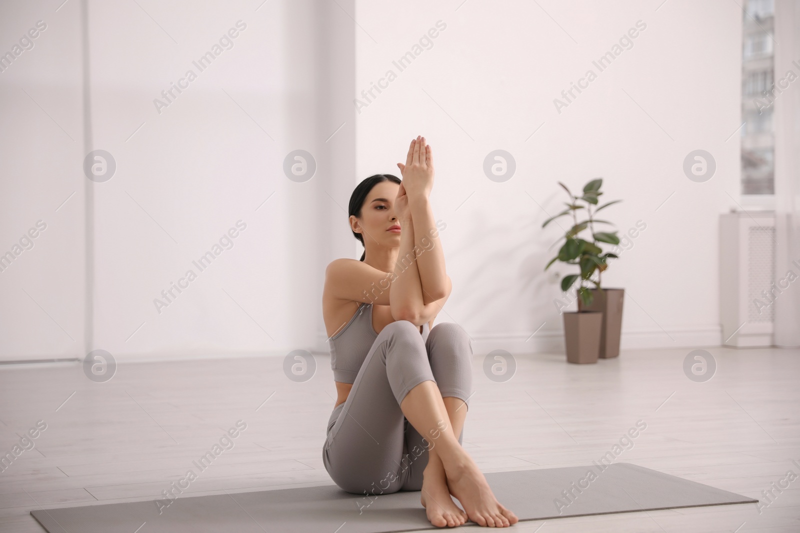 Photo of Young woman practicing eagle asana in yoga studio. Garudasana pose