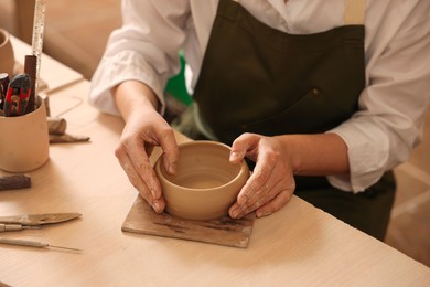Photo of Pottery crafting. Woman sculpting with clay at table indoors, closeup