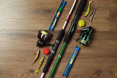 Photo of Spinning rods and fishing tackle on wooden background, flat lay