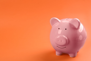 Photo of Pink piggy bank on orange background. Space for text