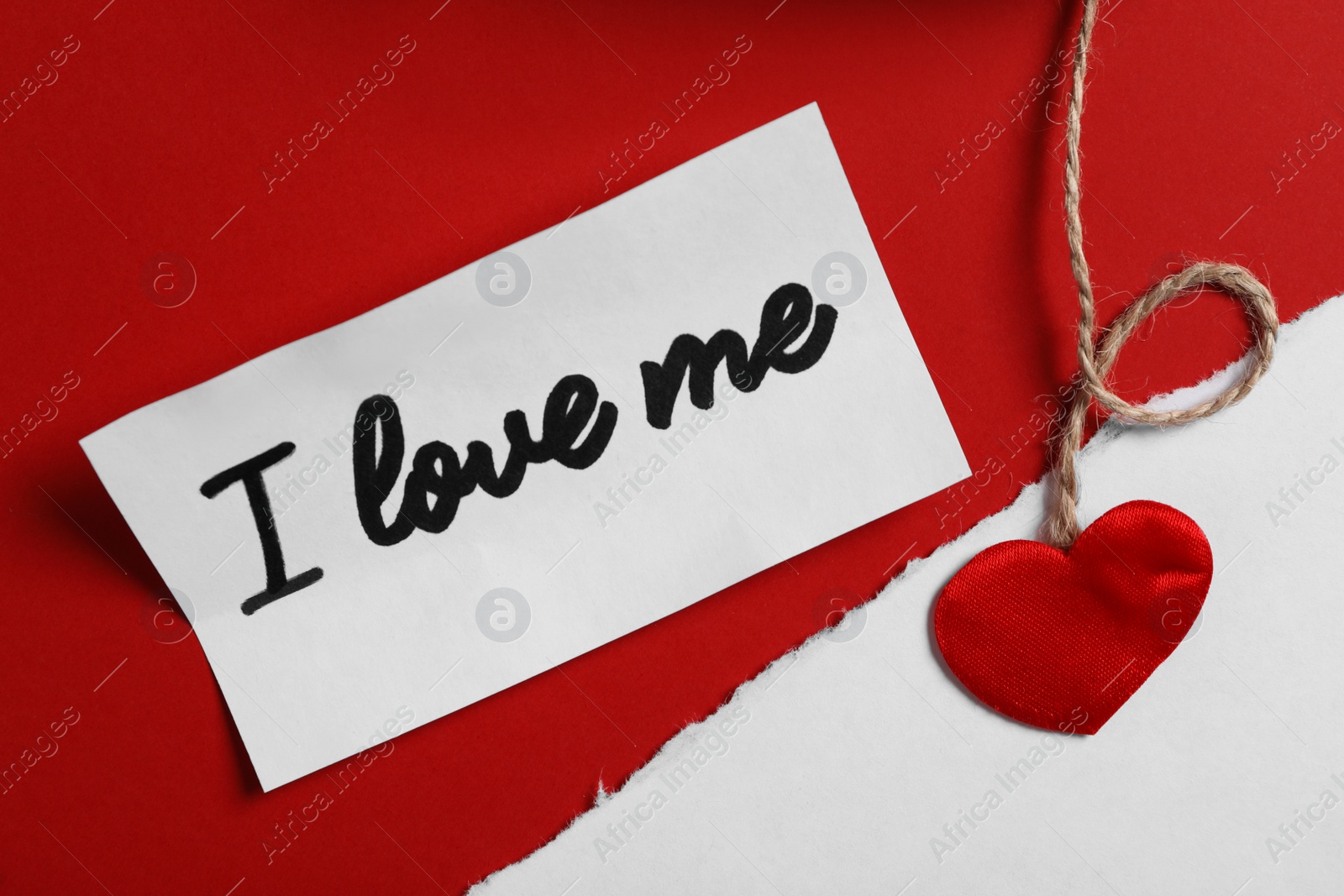 Photo of Paper with handwritten phrase I Love Me and heart on red background