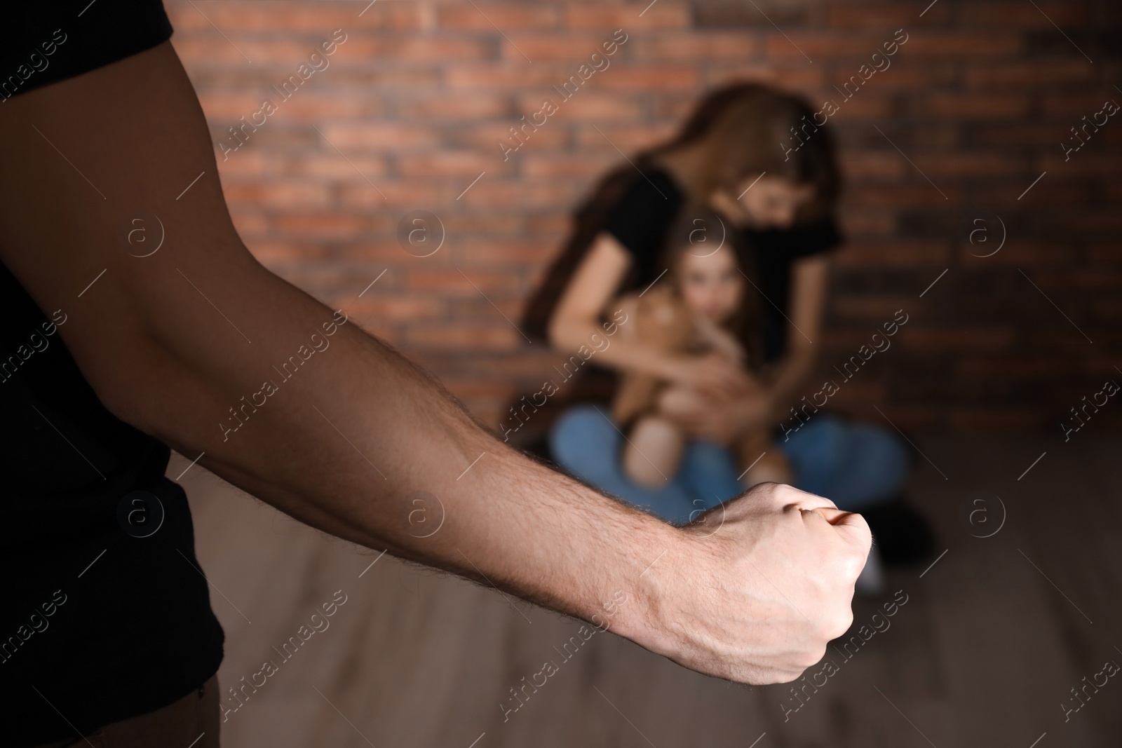 Photo of Man threatening his wife and daughter indoors, closeup. Domestic violence