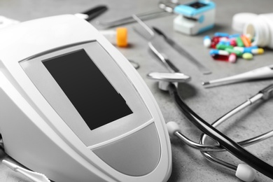 Photo of Digital pressure meter and medical objects on grey background, closeup. Space for text