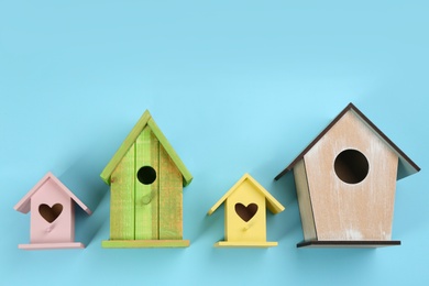 Collection of handmade bird houses on light blue background, flat lay