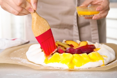 Woman making peach pie at kitchen table, closeup