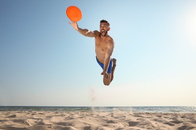 Sportive man jumping while trying to catch flying disk at beach