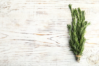 Bunch of fresh rosemary on wooden background, top view. Space for text