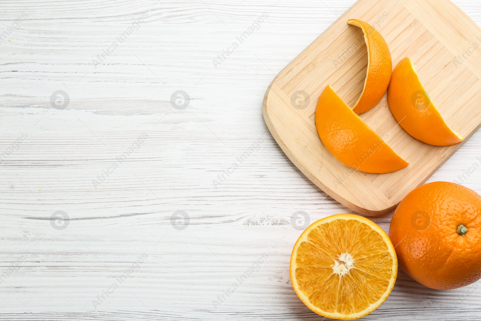 Photo of Orange fruits and peels on white wooden table, flat lay. Space for text