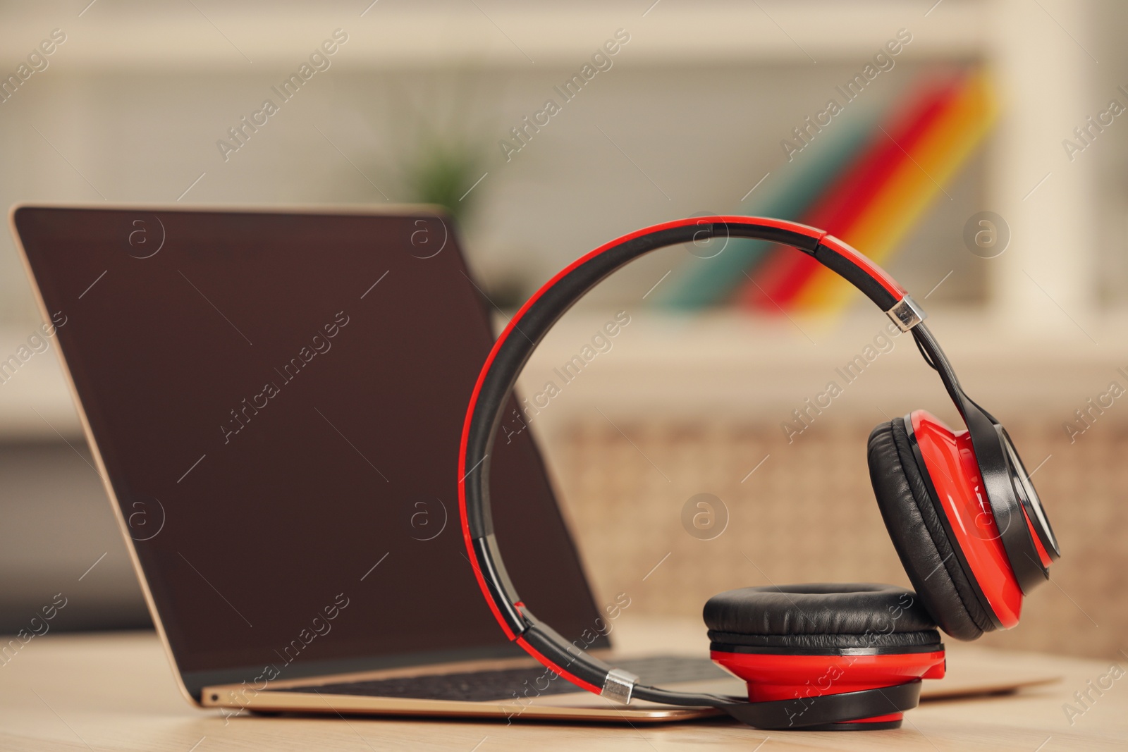 Photo of Modern headphones and laptop on table indoors