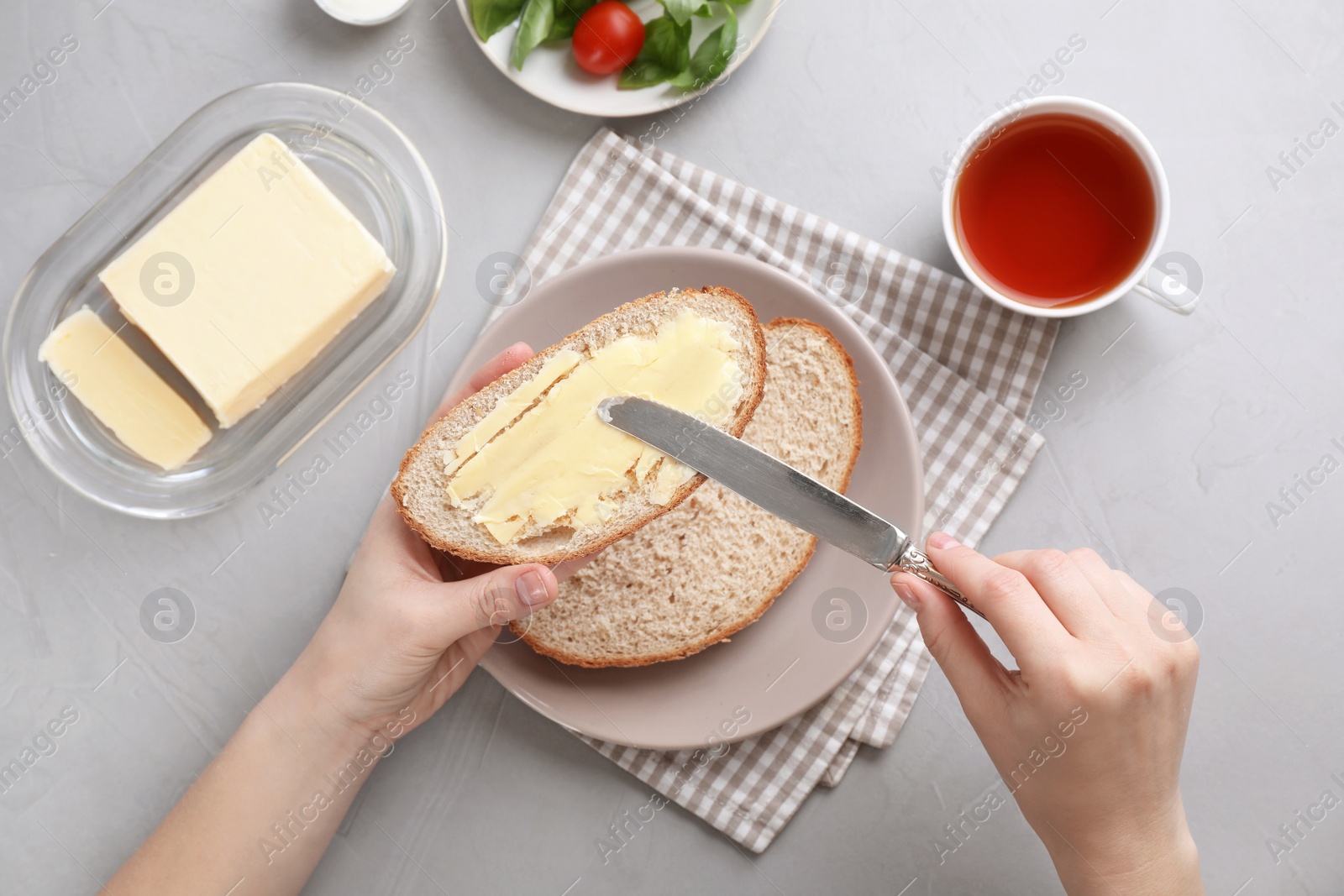 Photo of Woman spreading butter on slice of bread over table, closeup