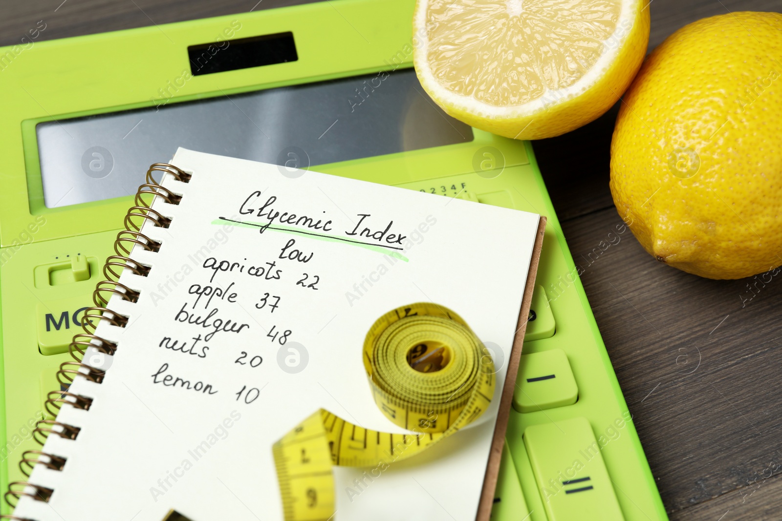 Photo of Notebook with products of low glycemic index, calculator, measuring tape and lemons on table, closeup