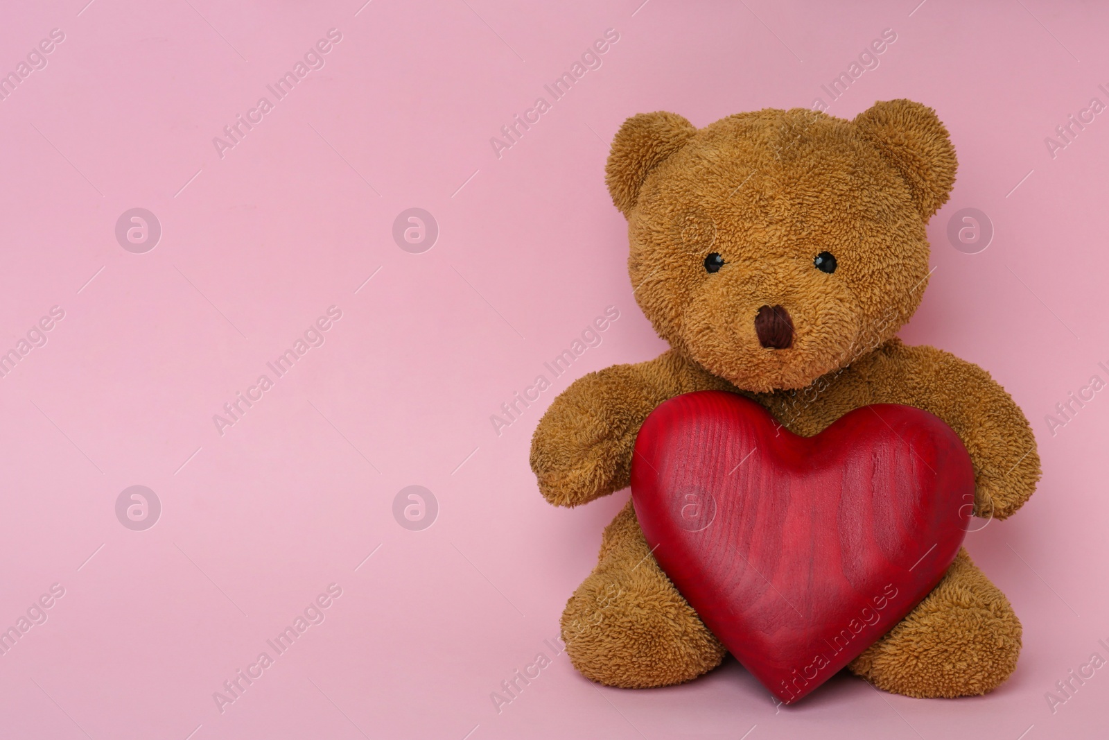 Photo of Cute teddy bear with red heart on pink background, space for text. Valentine's day celebration