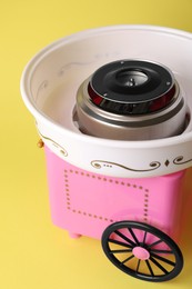 Photo of Portable candy cotton machine on yellow background, closeup