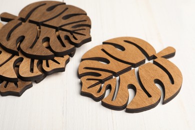 Leaf shaped wooden cup coasters on white table
