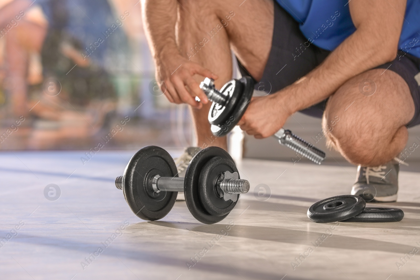 Photo of Male athlete with adjustable dumbbells indoors. Space for text