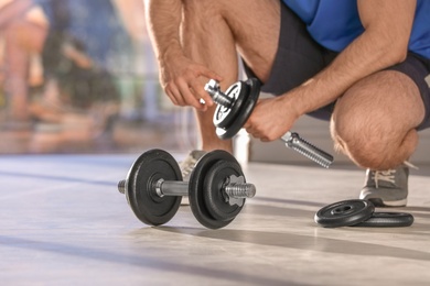 Photo of Male athlete with adjustable dumbbells indoors. Space for text