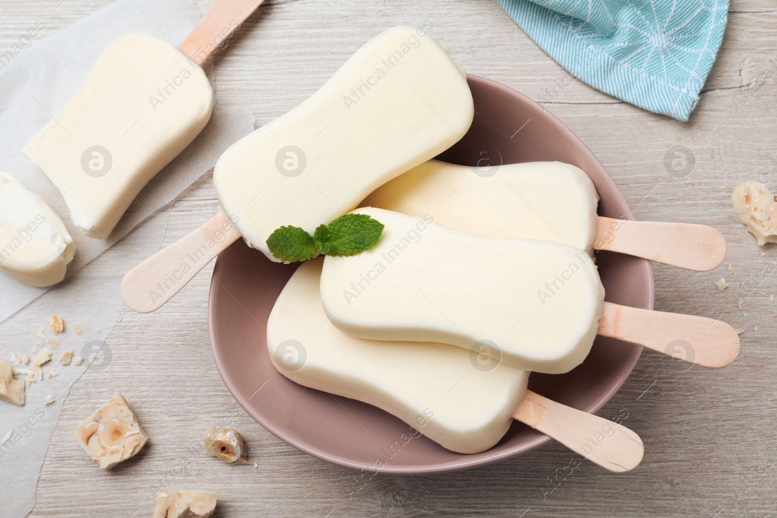 Photo of Delicious glazed ice cream bars, chocolate and mint on white wooden table, flat lay