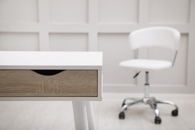 Photo of Modern white table with office chair indoors, closeup. Space for text