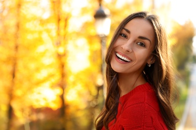 Photo of Beautiful woman wearing red sweater in sunny park. Autumn walk